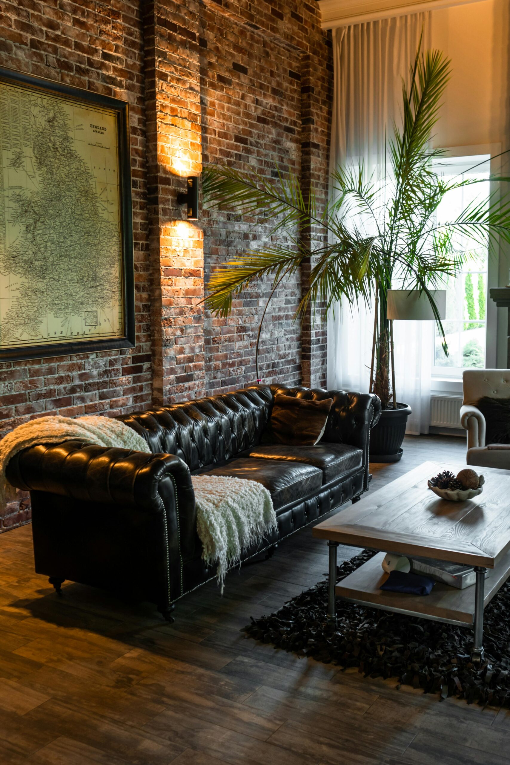 Stylish industrial-style living room featuring a leather sofa, rustic brick wall, and indoor plants.